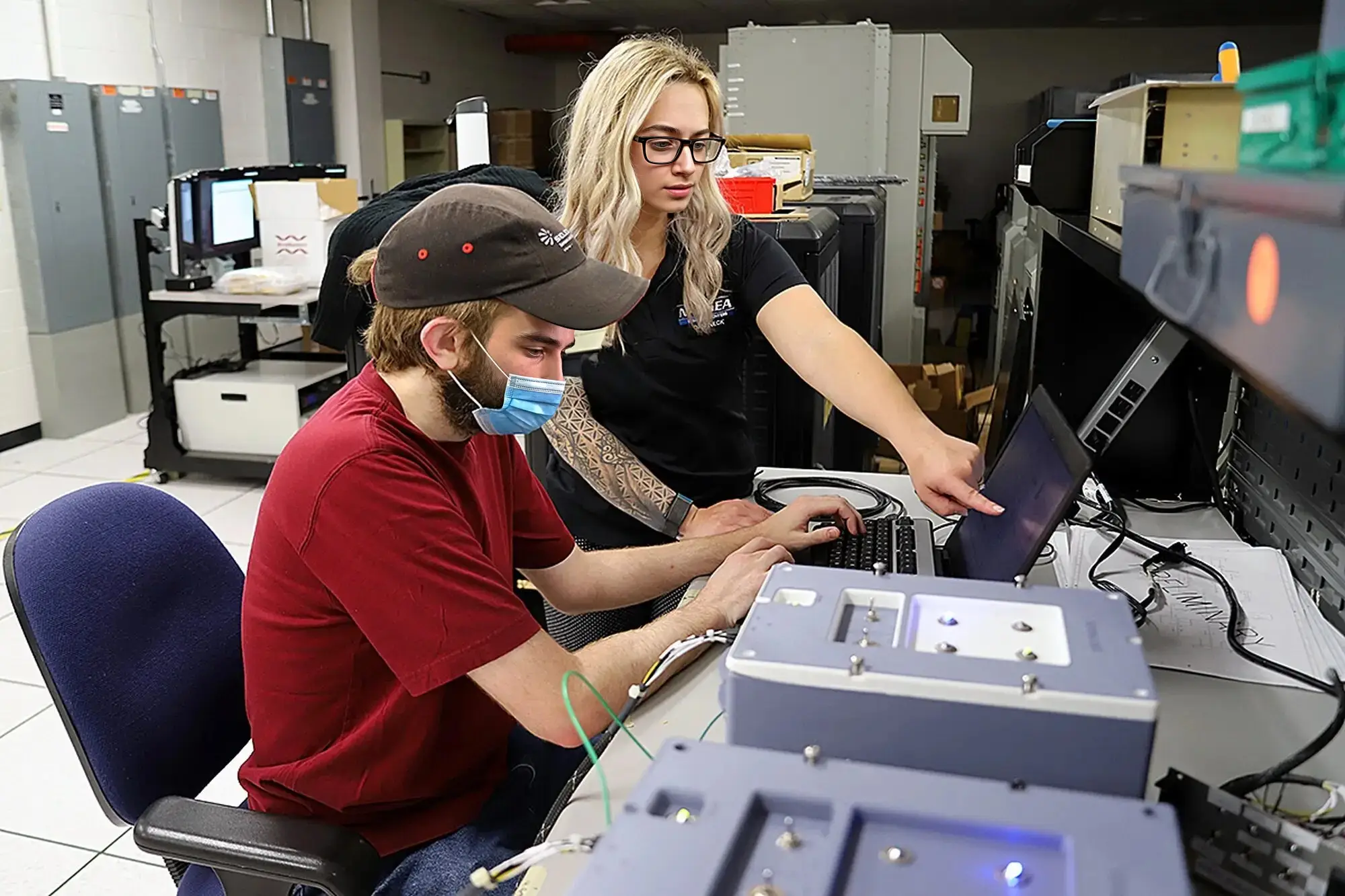 Two engineers testing hardware at a lab workstation