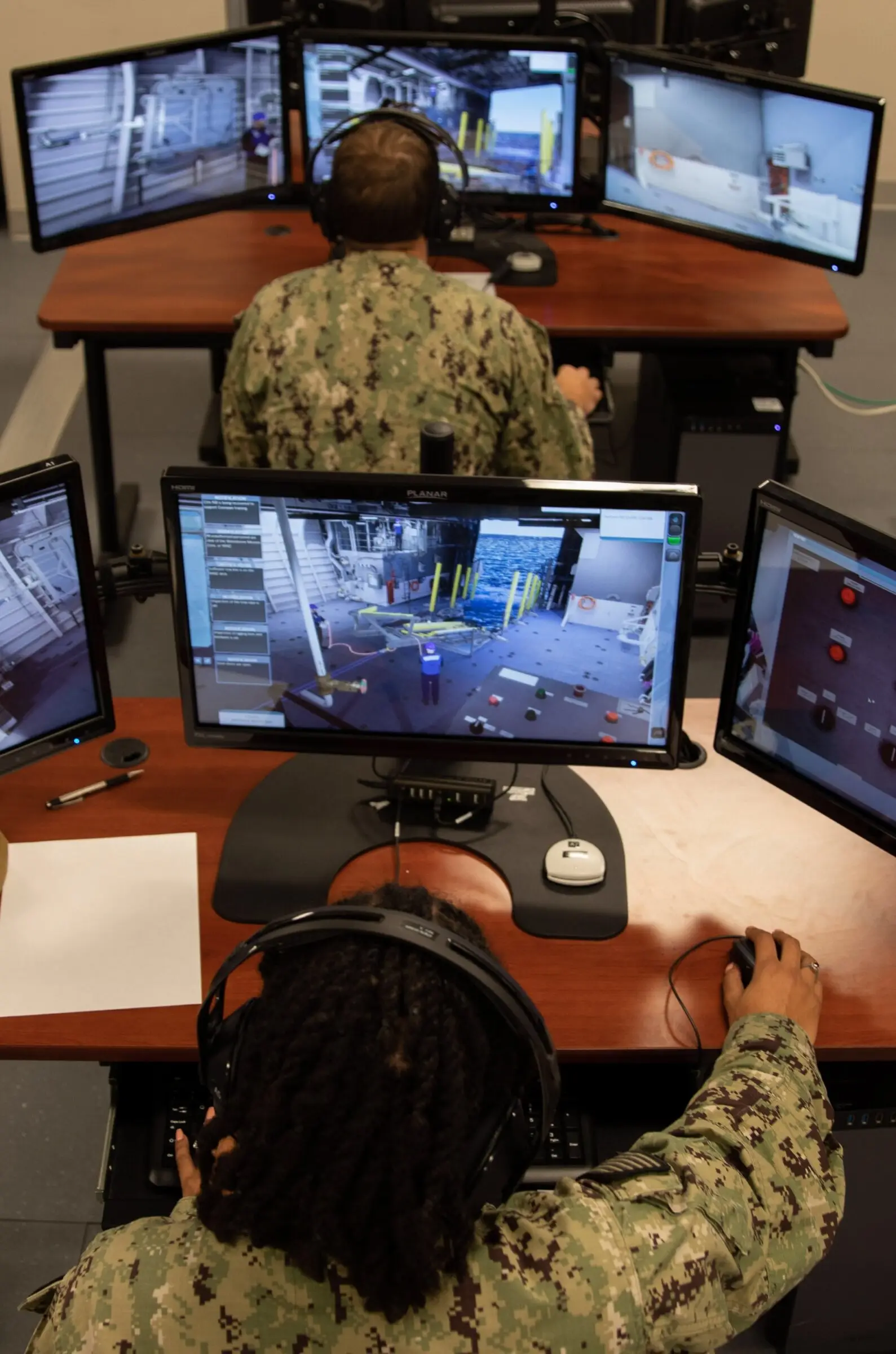 Trainee at a bank of virtual-environment training screens (portrait)