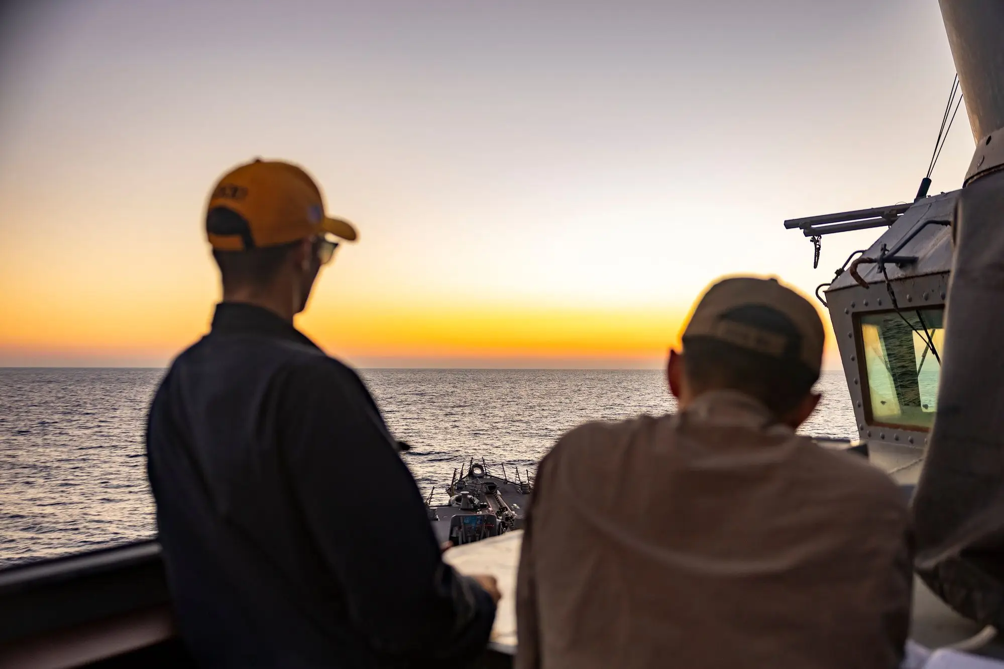 Two officers on a destroyer bridge wing watching the sunset
