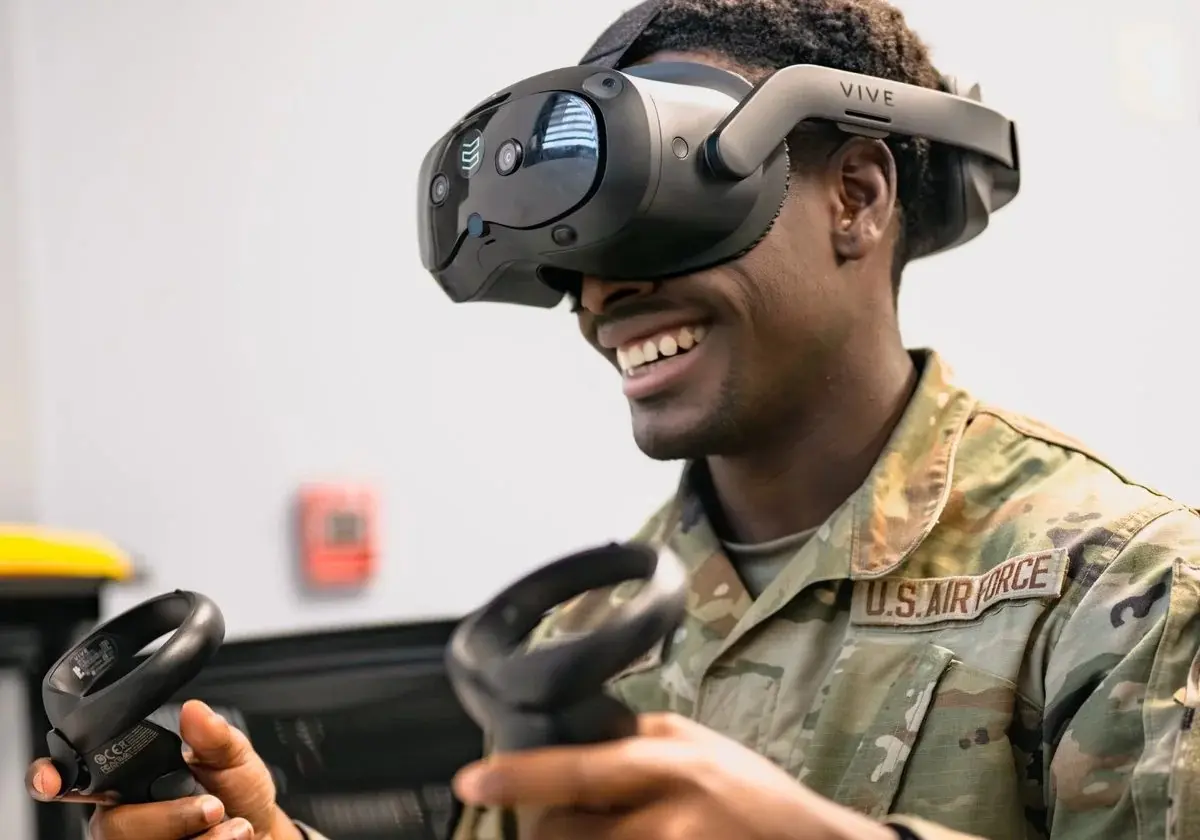 Airman smiling while training with a virtual reality headset and controllers
